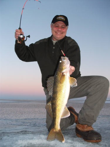 Fishing with Allen's Guide service: Holding up a fish caught with a rod and reel on the ice